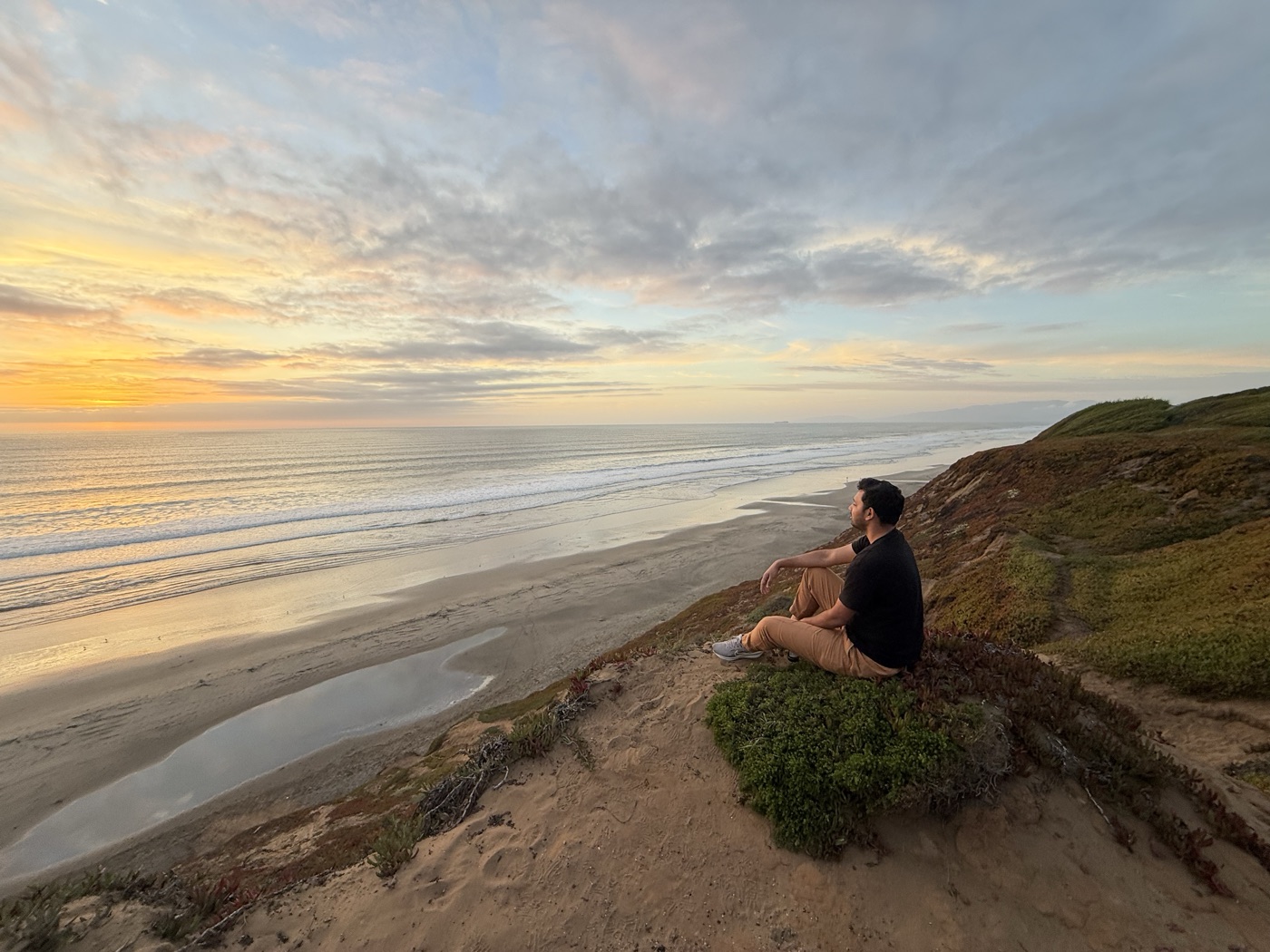 Shrey sitting on a cliff above the Pacific at sunset